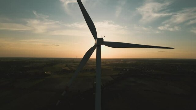 Aerial drone shot of a wind turbine at sunset, symbolizing clean and renewable energy in harmony with nature