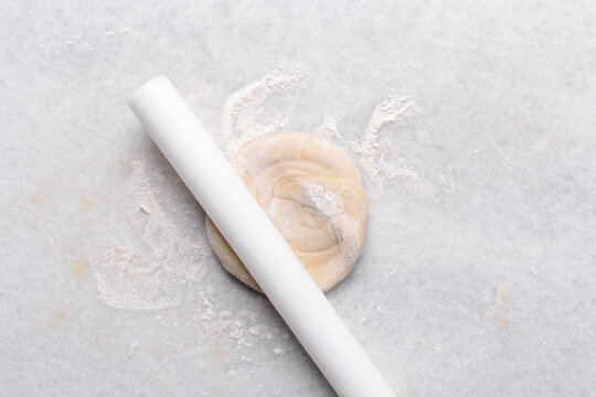 Overhead view of paratha dough being rolled out, top view of flaky flatbread dough, process of making paratha