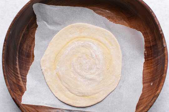 Overhead view of rolled paratha dough, top view of flaky flatbread dough, process of making paratha
