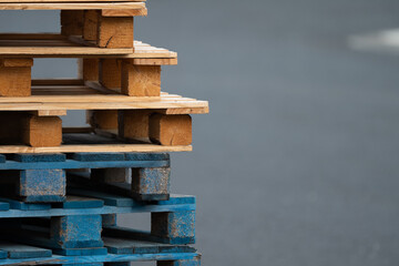 A stack of wooden pallets with one blue and one brown. The blue pallet is on top of the brown pallet
