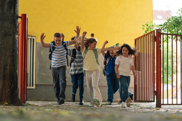 Happy pupils running out of school at the end of class