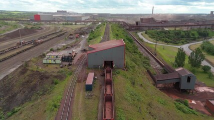 Aerial drone of train carts carrying raw materials ore from mines steel production facility industrial works England UK Scunthorpe railway 