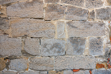Close-up of a weathered stone brick wall with textured surface patterns