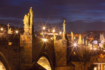 Illuminated Charles Bridge with baroque statues in Prague Czech Republic at night
