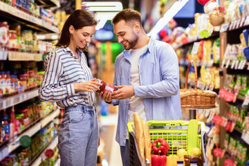 Customers In Super Market Concept. Young Family Couple Doing Grocery Shopping In Supermarket Choosing Healthy Products Buying Food Together Walking With Shop Cart In Groceries Store