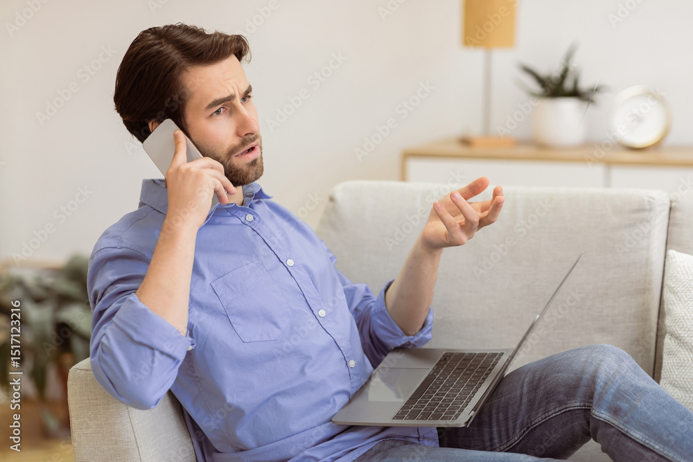 Poster discontented guy frowning talking on cellphone sitting with laptop, having computer or internet conn