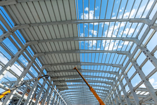 Covering is being done on precast roof. Interior view of the walls, supports, and roof of a precast commercial industrial prefabricated concrete. It is a construction product.