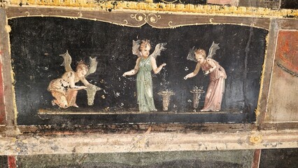 Pompeii, Italy – 8 January 2025. A black-ground fresco in the House of the Vettii shows three...
