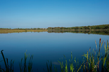 Panoramic landscape from the lake with colorful clouds in the summer sun.