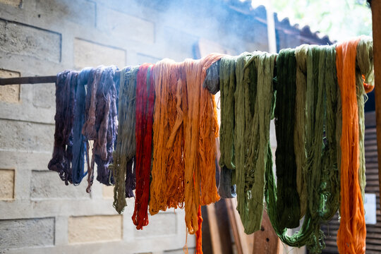 Naturally died skeins of cotton hanging on a rod to dry.