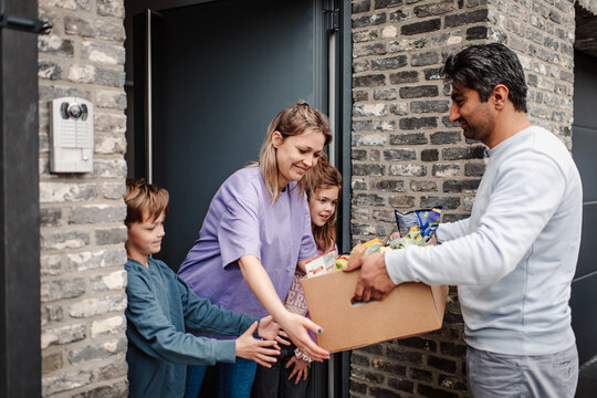 Doorstep delivery of groceries to a welcoming family