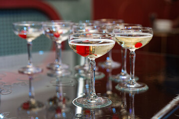 Champagne Glasses with Cherries on Reflective Table.