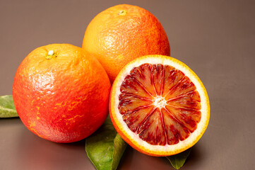 Sicilian sweet juicy yellow and red blood oranges with green leaves close-up