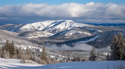 Fototapeta premium Snowy peak emerging through clouds, seen from a high-altitude ridge in winter