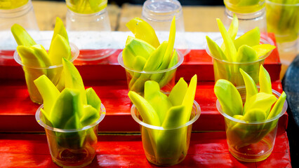 Pickled mango in plastic cups. A typical Indonesian snack made from sliced ​​young mango soaked in a solution of vinegar, salt, sugar, and spicy spices.