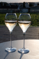 Glasses of white sparkling wine brut, grand reserve, champagne on green hilly vineyards in old wine making grand cru Ay-Champagne village in Vallee de la Marne, Champagne, France