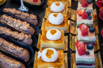 Variety of tasty French pastries, cakes, tarts, with cream and fruits on display in confectionery shop in France.