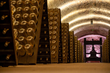 Bottles on racks in deep and long undergrounds caves, making champagne sparkling wine from...