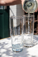 Waiter pouring mineral water from the glass bottle into a glass, food concept.