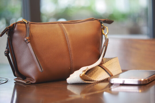 Brown leather handbag and smartphone on a table