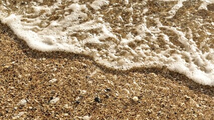 A close-up view of the waves retreating along the shore in slow motion, showing every bubble and...