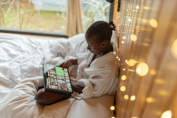 Woman relaxing in bed on the weekend and using iPad