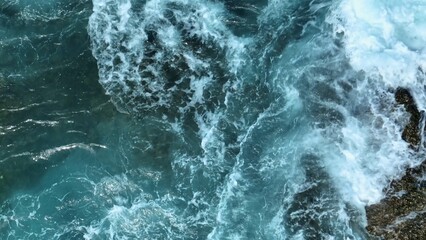 In slow motion, the ocean erupts against the rocks in an epic display of water and foam, capturing...