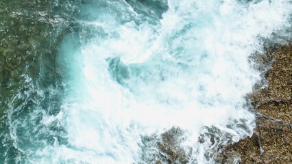 A breathtaking slow-motion aerial shot reveals the immense power of the ocean as towering waves crash against the jagged coastline, demonstrating nature’s boundless strength.
