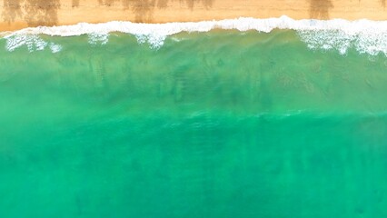 From above, the waves crash with intensity, sending sprays of water over the shore, illustrating...