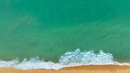 An epic aerial shot reveals the dynamic energy of the sea, where waves collide powerfully with the...