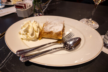 Austrian desserts, piece of apple strudel with whipped cream served in old traditional bakery cafe in Vienna, close up