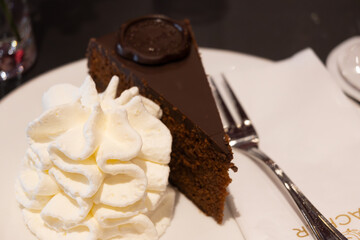 Piece of famous Sachertorte chocolate cake with apricot jam of Austrian origin served with whipped...
