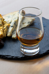 Whiskey and cheese pairing, tasting whisky glass and plate with sliced blue stilton and blue shropshire cheeses, Great Britain food and drink