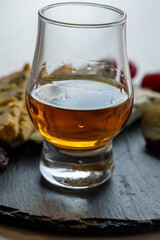 Whiskey and cheese pairing, tasting whisky glass and plate with sliced blue stilton and blue...