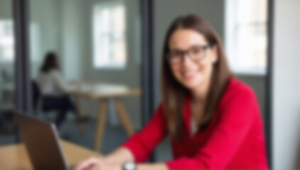 Blurred office scene showing professional woman at desk. Image is suitable for business, workplace, or technology concepts.