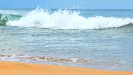 A serene beach scene with gentle ocean waves crashing against the golden shore, capturing the beauty of nature and tranquility under clear blue skies. Thailand.
