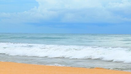 The waves of the sea rise and crash onto the beach, creating a dynamic scene of motion and beauty, with the horizon stretching into the distance. Thailand.
