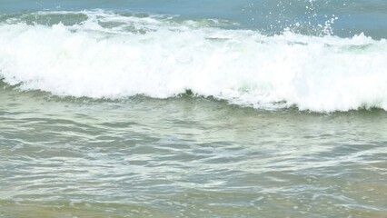 A beautiful view of ocean waves forming frothy patterns as they crash against the shore. The clear water and foam bring life to the beach, evoking a sense of tranquility and natural beauty.
