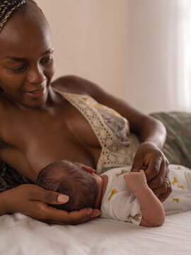 Woman observing baby hand while breastfeeding