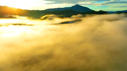 A mist-covered valley at sunrise, with light piercing through the fog and casting a golden hue. The...