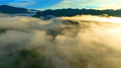 A drone shot of mist rolling over the mountains at sunrise, with golden light breaking through the...