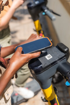 People scanning QR code on rental public e-scooter to hire it