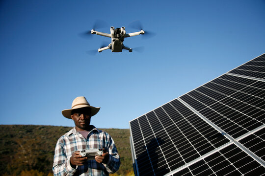 Farm worker taking drone photography of solar panels.