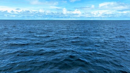 Obraz premium A tranquil aerial view of the vast ocean, showcasing the endless blue waters under a sky filled with soft clouds, perfect for themes of serenity, nature, and expansive landscapes. Phuket, Thailand. 