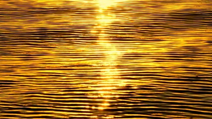 A stunning aerial shot capturing the golden hues of sunlight reflecting off the calm water,...