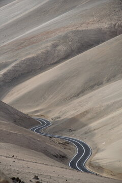 Remote tar road winding through desert mountains.