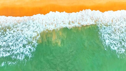 An aerial view of the ocean's turquoise water meeting a sandy shore, with waves gently crashing, evoking a calm, tropical beach vibe perfect for nature and travel content. Phuket, Thailand.

