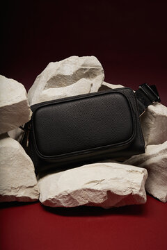 Minimalist black bag resting on light stone blocks