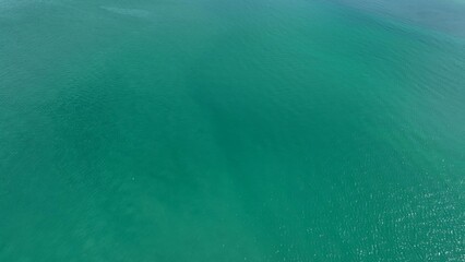 A stunning aerial shot of the ocean's smooth, turquoise water, capturing the natural beauty and...