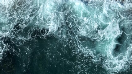 The fierce interaction of waves and rocks under the influence of strong winds, with foamy water...